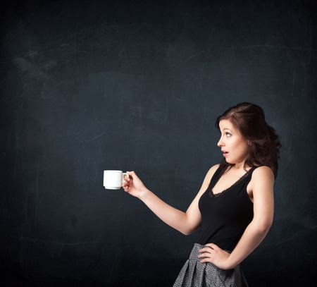 businesswoman-standing-holding-white-cup-black-339750128 Businesswoman standing and holding a white cup on a black background