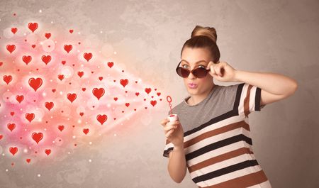 Pretty young girl blowing valentine red heart symbols