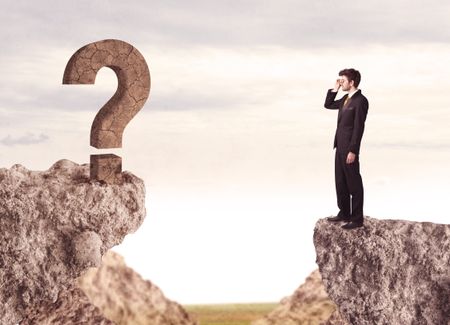 Businessman standing on the edge of mountain with a rock question mark on the other side 