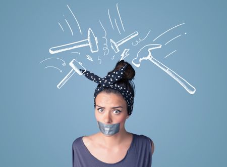 Young woman with taped mouth and white drawn beating hammer marks around her head