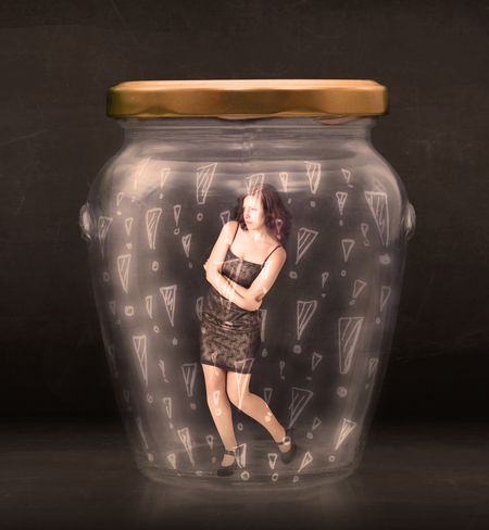 Business woman trapped in jar with exclamation marks concept on bakcground