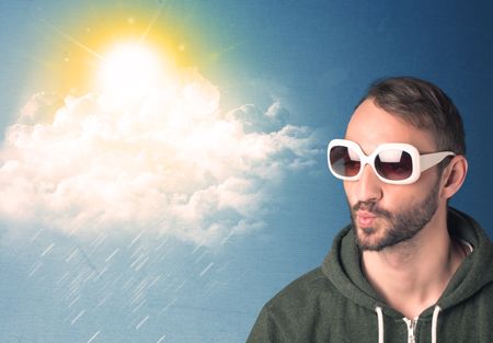 Young person looking with sunglasses at clouds and sun concept on blue background