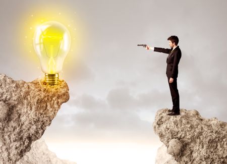 Businessman standing on the edge of mountain with an idea bulb on the other side 