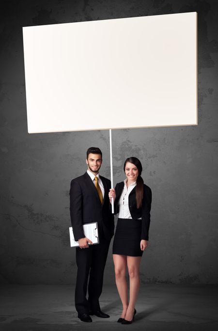 Young business couple holding a blank whiteboard