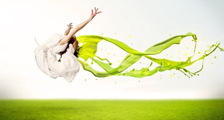 Pretty girl jumping with green abstract liquid dress concept in nature