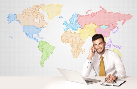 Businessman sitting at white table with colorful world map background