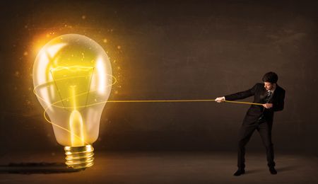Business man pulling a big bright glowing light bulb concept on background