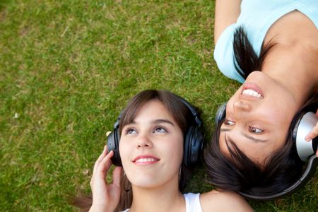 Women lying on grass listening to music