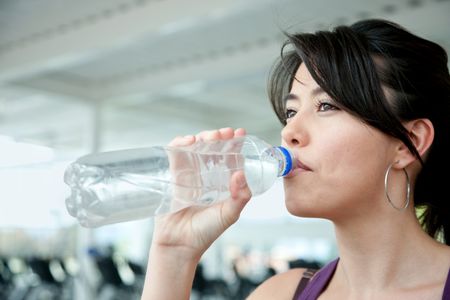 Portrait of a beautiful woman drinking water at the gym