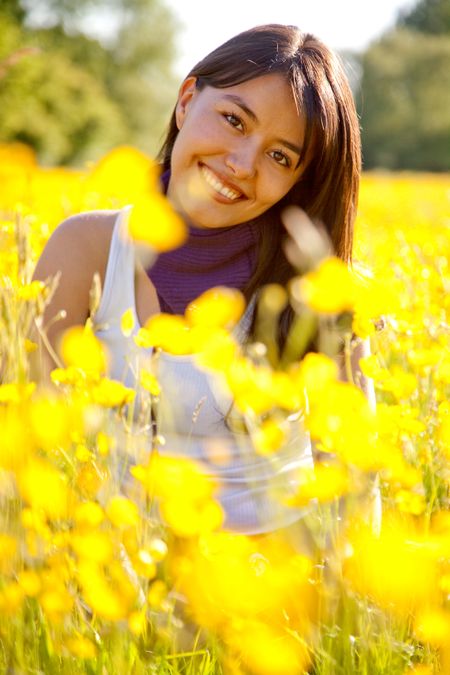 casual woman smiling outdoors with yellow flowers