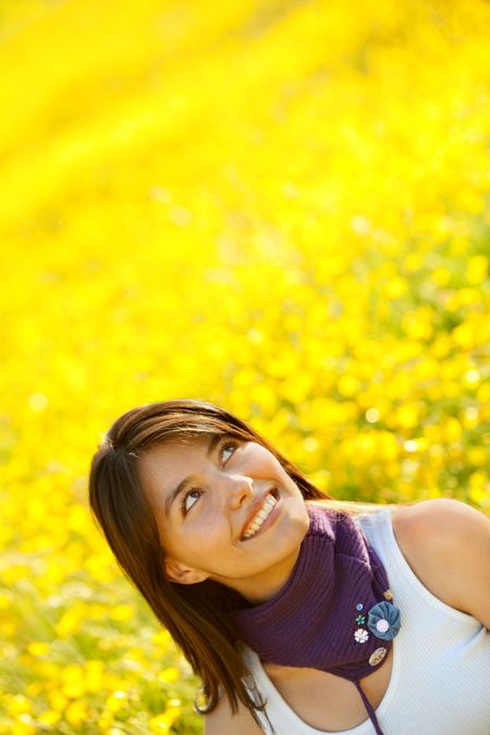 casual woman smiling outdoors with yellow flowers