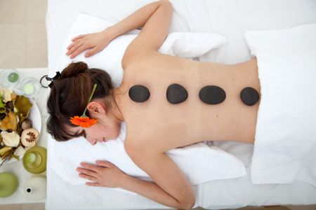 Beautiful woman relaxing at a spa with stones on her back