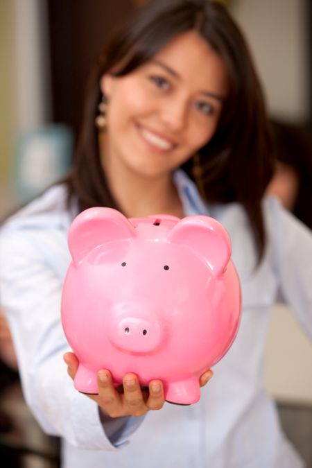 Smiley woman with a piggy bank in an office