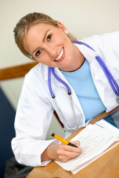 female doctor smiling and writing at the hospital