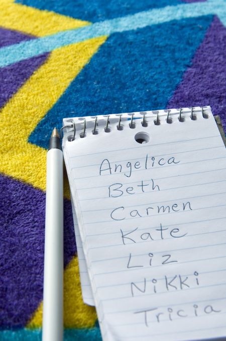 List of female names on pocket notebook on beach towel