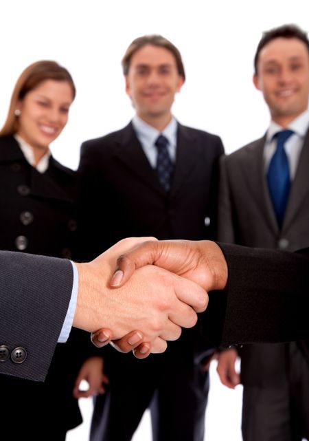 Partners handshaking in front of a group of business people