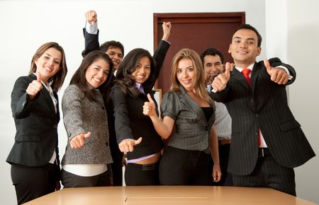 Business group in an office with their thumbs up