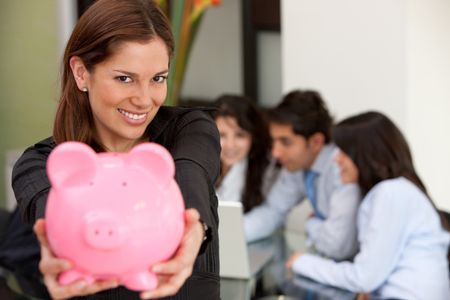 Business woman at an office holding a piggy bank