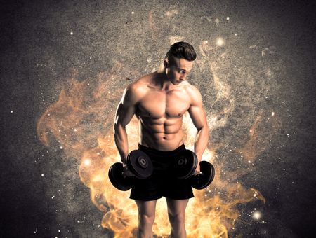 A strong athletic guy looking seductive while working out with weight in front of a burning fire concrete wall and big flames concept