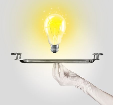 Serving a bright business idea concept using a bulb with bright sparkling warm yellow light presented on a silver plate
