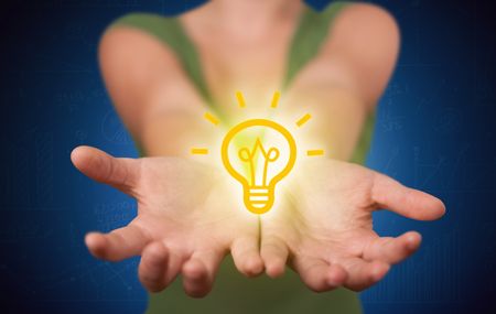 A creative businessman has a great bright idea illustrated by holding a drawn light bulb in the hand concept