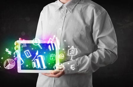 Young person holding white tablet with graph and chart symbols