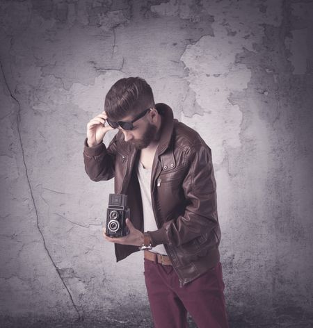 Funny vintage guy with long beard and stylish hair standing in front of urban concrete wall concept