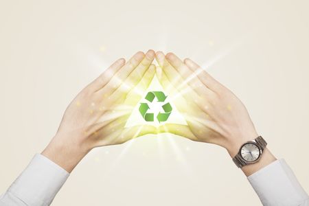 Hands creating a form with green recycling sign in the center