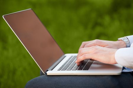 Businessman pressing modern laptop computer on colorful office background