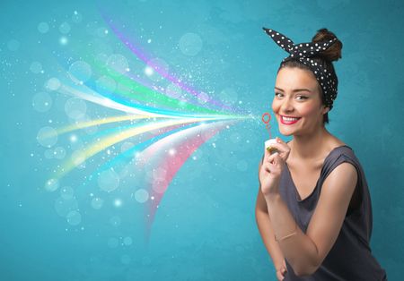 Beautiful girl blowing abstract colorful bubbles and lines on blue background