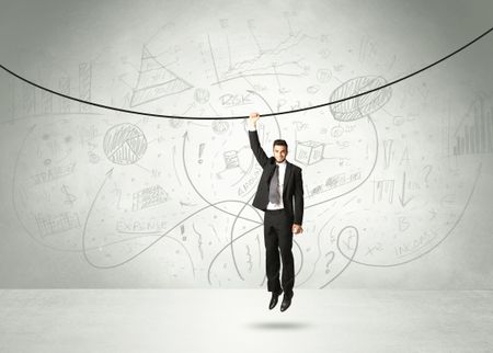 Businessman hanging on a rope with analysis and graphs background
