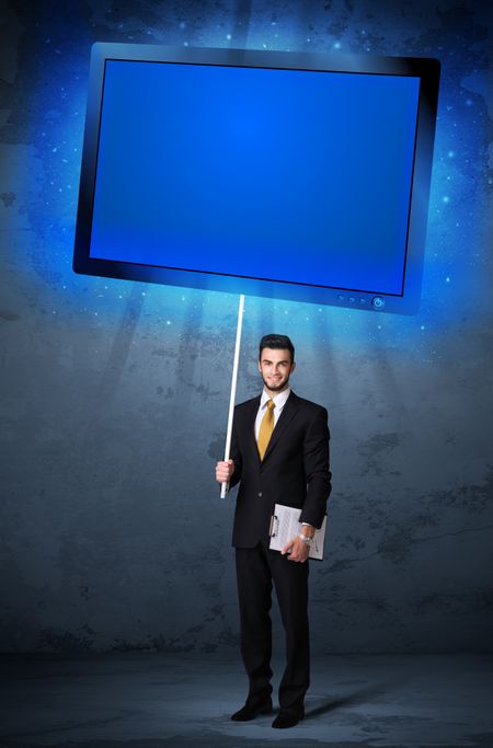 Young businessman holding a big, blue shining tablet
