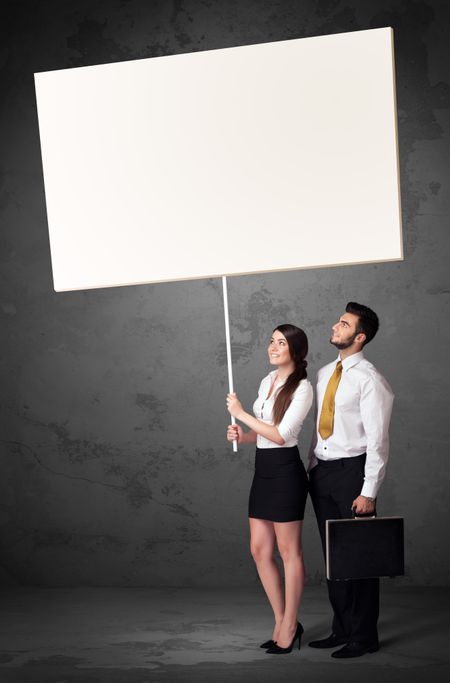Young business couple holding a blank whiteboard