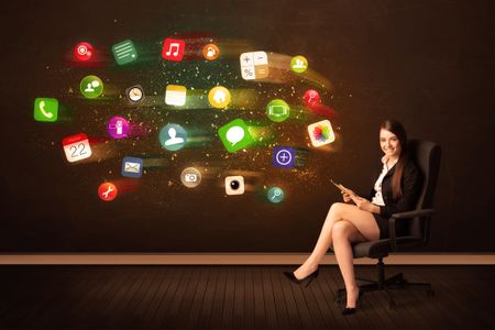 Business woman sitting in office chair with tablet and colorful app icons concept on background
