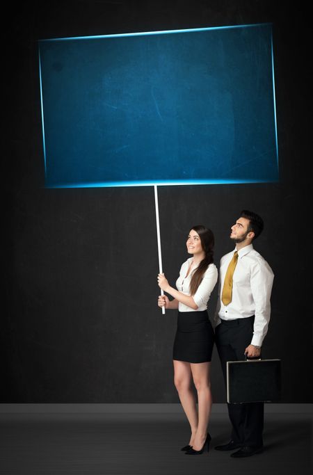 Young business couple holding a big, blue board
