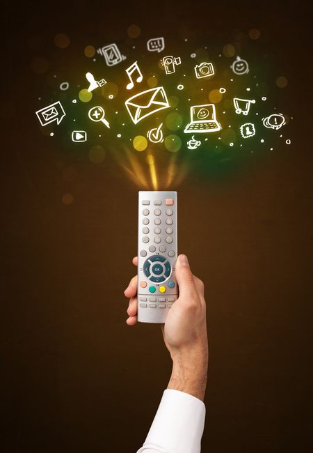 Hand holding a remote control, social media icons coming out of it
