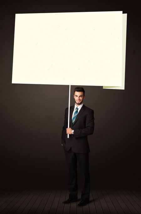 Young businessman holding a big, white post-it paper
