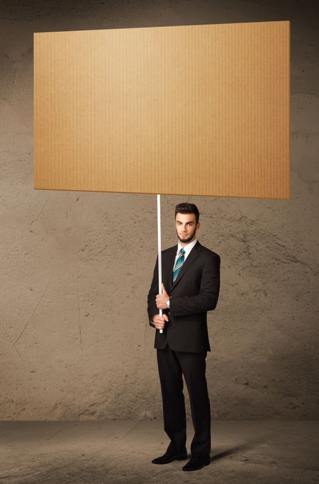 Young businessman holding a blank brown cardboard
