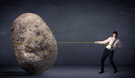 Businessman pulling huge rock with a rope concept on background