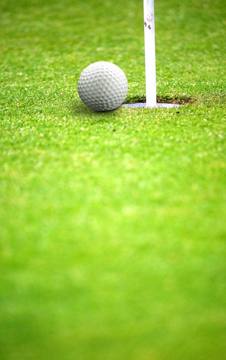 golf ball very near a flag hole