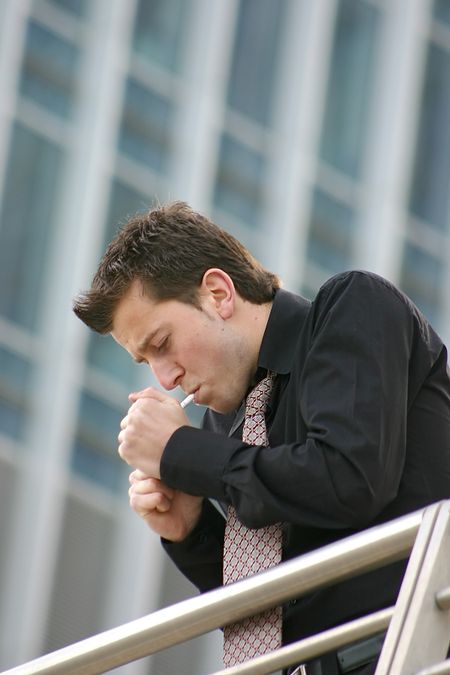 business man lighting a cigarette in a corporate environment
