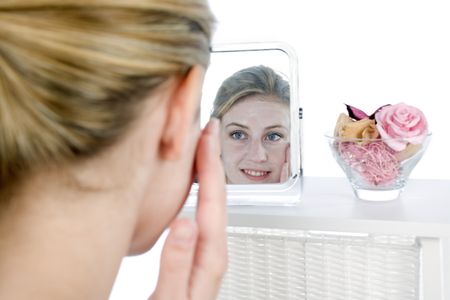 Female model looking into mirror applying cream