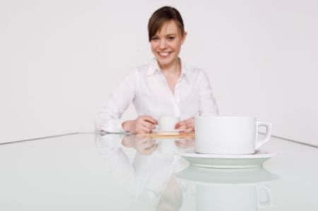 Businesswoman smiling in soft focus with a cup of coffee in the foreground.