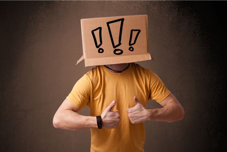 Young man standing and gesturing with a cardboard box on his head with exclamation point