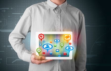 Young businessman presenting modern tablet with colorful social signs and icons