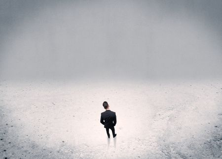 An adult elegant businessman standing in the middle of nowhere in empty grey concrete space background concept