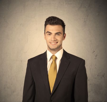 A young handsome business person making facial expression in front of clear, empty concrete wall background concept