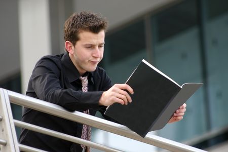 business man reading a black manual with an experssion of boredom