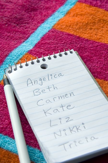 List of female names on pocket notebook on beach towel