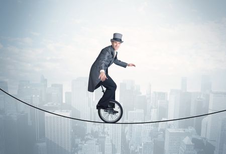 Brave guy riding a monocycle on a rope above cityscape concept